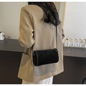 Detail of minimalist black cylindrical shoulder bag with sleek leather strap and zipper