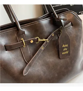 Detailed macro view of vintage brown leather tote bag showing shiny gold metal hardware