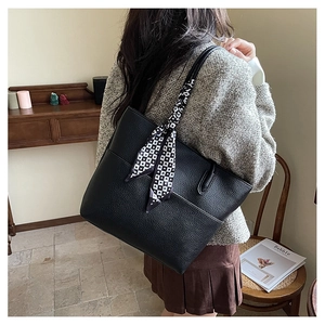 Detail of black pebbled leather tote bag with a decorative geometric pattern silk scarf