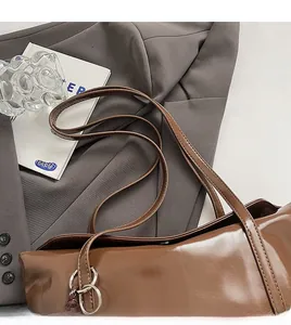 Close-up of brown glossy shoulder bag showing smooth stitching and silver metal rings