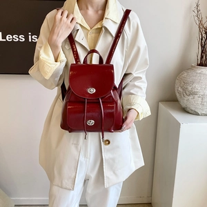 Detail view of burgundy shiny leather backpack featuring silver twist-lock and drawstring