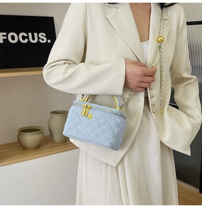 Detail showing the light blue quilted mini box bag with gold chain and metal handle
