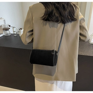 Detail view of a black minimalist cylindrical crossbody bag in soft matte texture