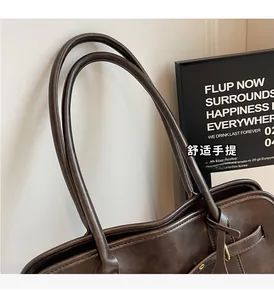 Detailed close-up of dark brown leather tote bag handles with elegant gold hardware accents
