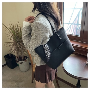 Detail of black pebbled leather tote bag with geometric scarf and long shoulder strap