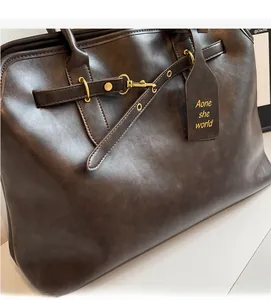 Close-up of retro brown leather handbag showing gold hardware and decorative strap details
