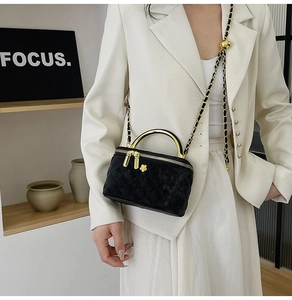 Detail of black quilted velvet bag with gold handle and chain on a model