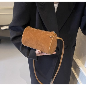 Detail shot of a brown suede cylinder bag styled with a black blazer for daily outfits