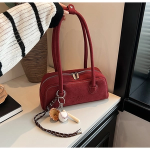 Detail view of burgundy suede handbag featuring decorative baseball theme charms