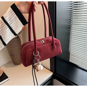 Detail of burgundy suede underarm bag with double straps and sports theme charm