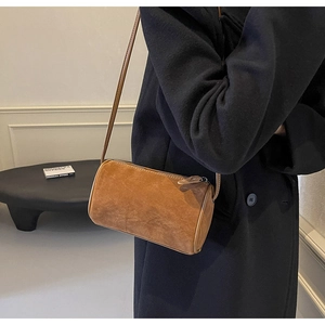 Macro detail of the brown suede cylinder crossbody bag showing the soft velvet-like texture