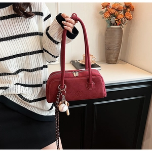 Detail of burgundy matte shoulder bag with dual zipper and mini baseball charm