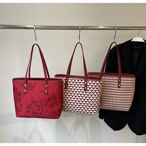 Detailed close-up showing three red bridal tote bags with floral, heart, and checkered textures
