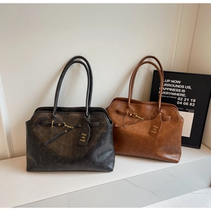 Detail of vintage tote bags with horizontal buckles and gold hardware on marble surface