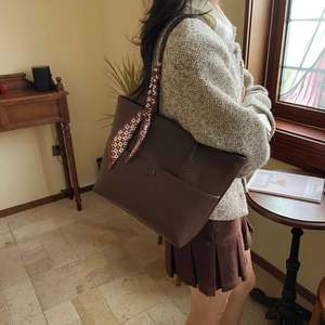 Detail view of deep brown leather tote bag with printed silk scarf on the shoulder strap
