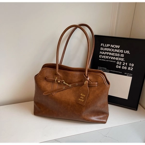 Detailed close-up of brown vintage PU leather tote bag with decorative buckle and tag