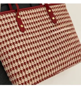 Detail view of red houndstooth tweed tote bag featuring leather handles and gold metal rivets
