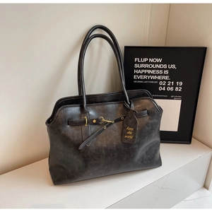 Close-up of retro black tote bag with vintage leather texture and gold buckle detail