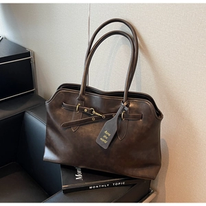 Detail view of vintage dark brown faux leather tote with metal buckle and long straps