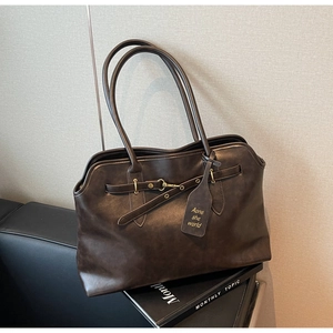 Detail view of deep brown vintage leather tote with metallic buckles and thin straps