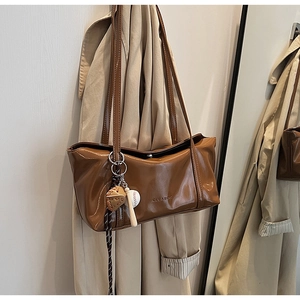 Close-up of brown glossy leather shoulder bag with clear logo and baseball glove charms