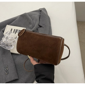 Detail of coffee brown cylindrical crossbody bag in faux suede with leather trim