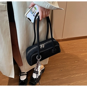 Detail of black cylinder underarm bag featuring white stitching and silver double zippers
