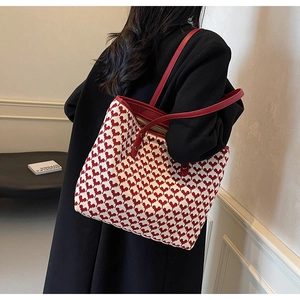 Detail of red and white woven tote bag with heart patterns and leather shoulder strap