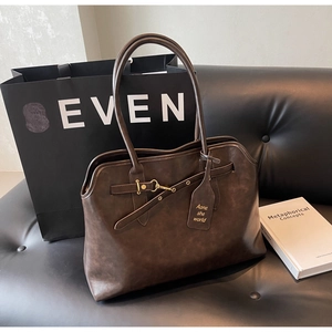 Detailed view of deep brown vintage leather tote bag with gold metallic buckle accents