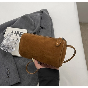 Detailed view of brown suede cylinder crossbody bag showing size and smooth leather trim