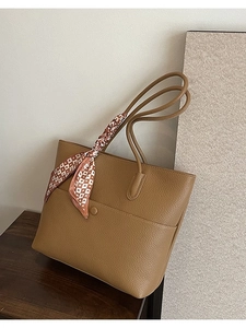 Brown lychee leather tote bag with elegant printed silk scarf on a wooden tabletop