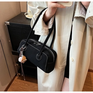 Detail of black canvas shoulder bag with baseball charm and embossed sports logo