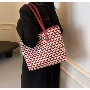Detail of red and white heart pattern tote bag with leather straps and metal rivets