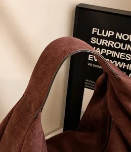 Close-up of brown suede tote bag handles with detailed edge paint and fine leather texture