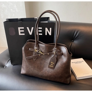Detail of vintage dark brown tote bag with metal buckles and soft leather texture