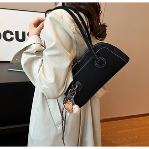 Detail view of black cylinder shoulder bag with contrast stitching and baseball charm