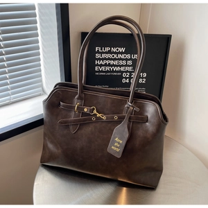 Detail view of deep coffee vintage tote bag with retro leather texture and brass metal buckle