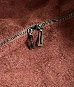 Close-up of dual silver metal zippers on a rust red suede tote bag for women