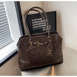 Detail view of large dark brown retro tote bag with golden hardware and leather tag