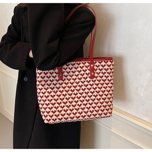 Red heart pattern knit tote bag shown from side profile with black coat outfit style
