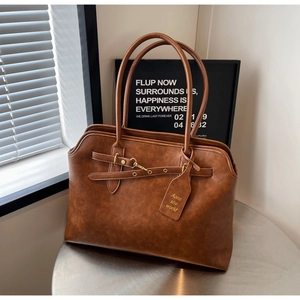 Detailed view of vintage brown tote bag with leather straps and silver hardware buckles