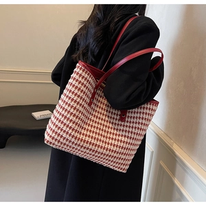 Detail of red houndstooth tote bag featuring premium leather straps on female model