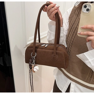 Brown suede underarm bag with baseball pendant shown in a mirror selfie outfit