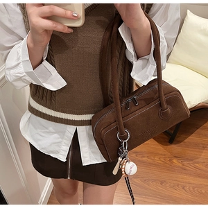 Detailed close-up of brown suede Boston bag with sporty charms and brand embossing