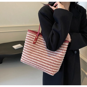 Detail of red and white houndstooth tweed tote bag with leather straps and gold rivets