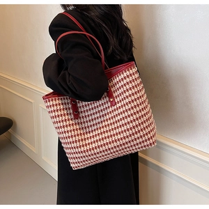 Detail of red and white houndstooth tote bag featuring premium leather straps and trim