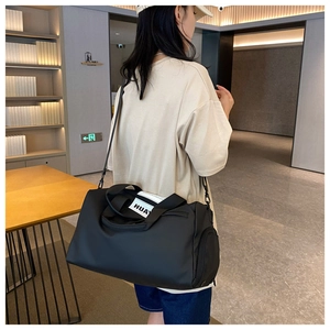 Close-up of the black sports bag featuring durable webbing handles and side zip pocket