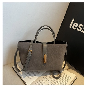 Detailed macro view of the grey faux suede texture and gold oval buckle on the tote bag