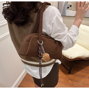 Detailed close-up of brown suede cylindrical shoulder bag with white contrast stitching