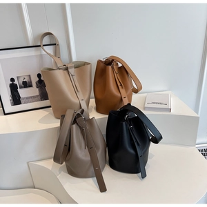 Minimalist leather bucket bags in beige, brown, grey and black on display stands